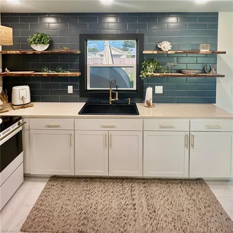 Quartz Counter Tops, White Cabinetry, Live-Edge Open Shelving, Navy Blue Subway Tile Backsplash, LED Lighting.