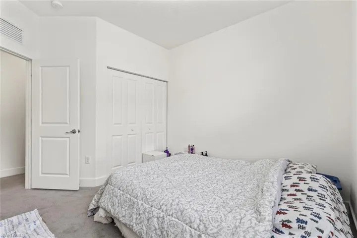 Bedroom with light carpet and a closet