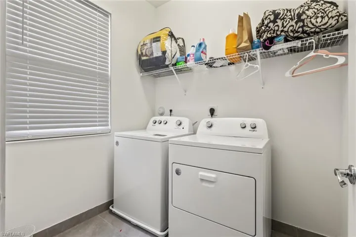Washroom with separate washer and dryer and light tile patterned flooring