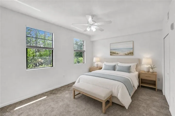 AI Staged. Large bedroom with new carpet, two windows with new blinds, ceiling fan with lighting, and newly painted