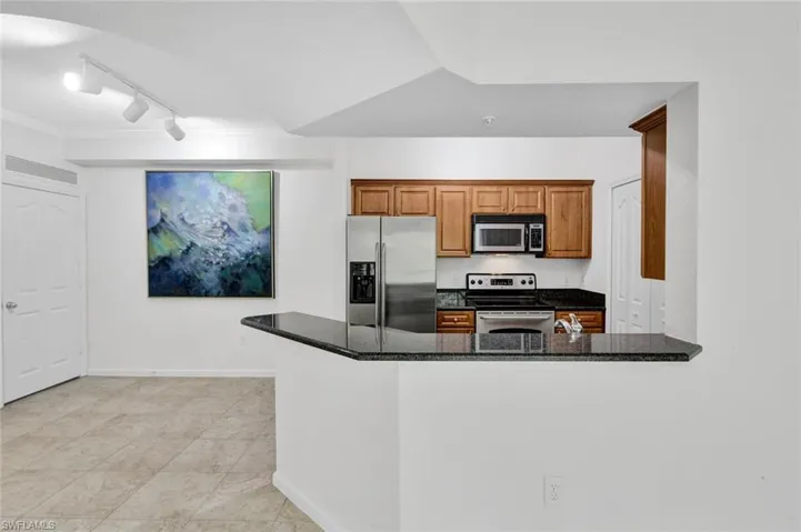 Kitchen and dining area featuring wood cabinetry, granite countertops, and stainless steel appliances