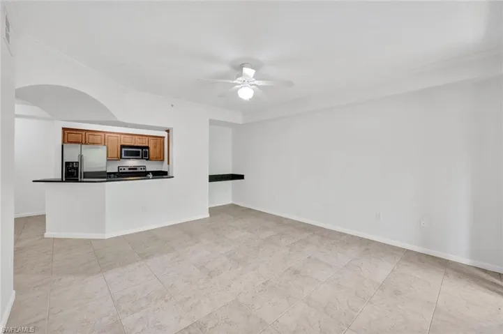 Freshly painted tiled living area, ceiling fan with light, crown molding, built-in desk with granite top, and kitchen pass-through