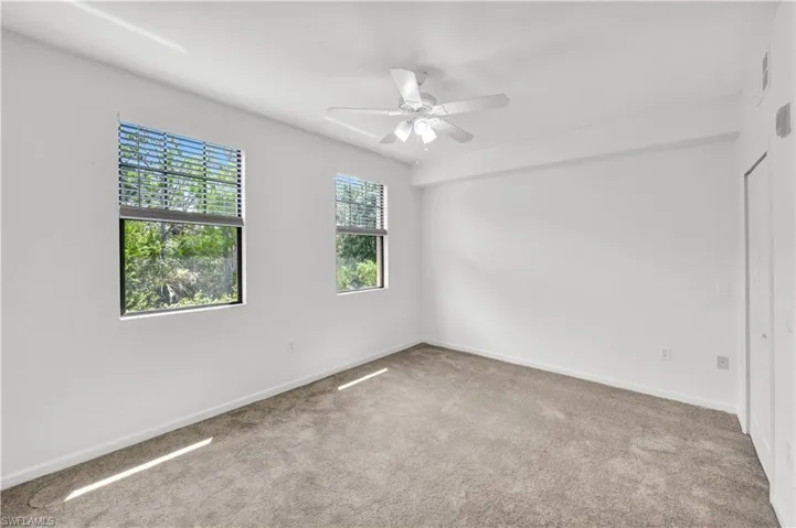 Freshly painted, light, bright spacious bedroom with two windows and new blinds, new carpet, and a ceiling fan with lighting