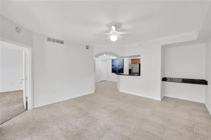 Light and bright open living floor plan with built-in desk, freshly painted, crown molding, and bedroom to the left