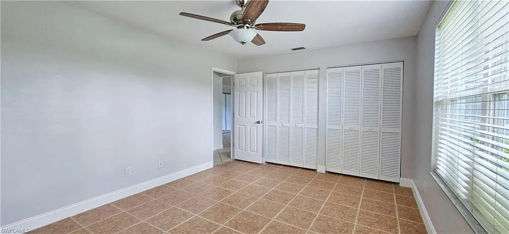 Unfurnished bedroom featuring ceiling fan, multiple closets, and tile flooring