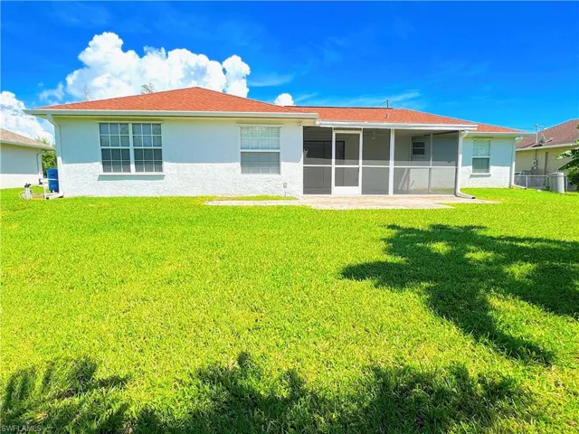 Rear view of property with a yard, screened lanai, and pavered outdoor porch