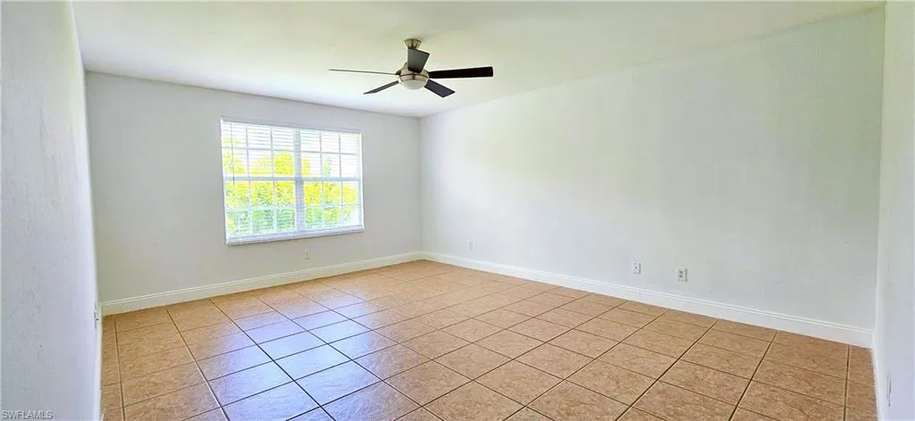 Tiled Primary bedroom featuring ceiling fan, walk-in closet, and on suite bathroom