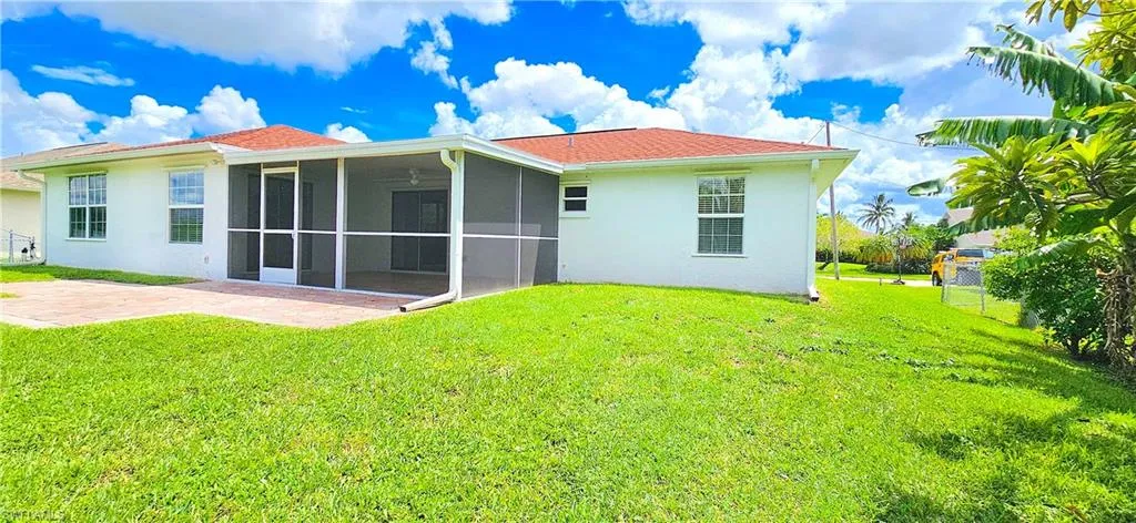 Back of house featuring a screened lanai, yard, and a patio with pavers