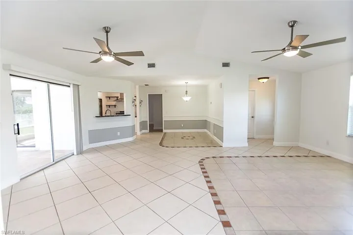 Tiled room featuring vaulted ceiling and 2 ceiling fans