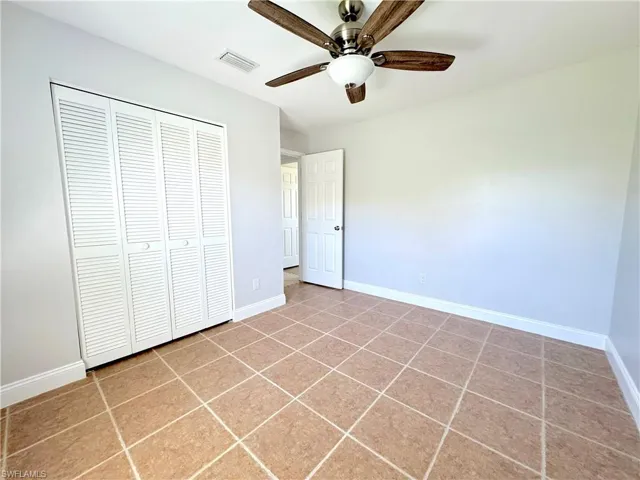 Unfurnished bedroom with a closet, ceiling fan, and tile floors