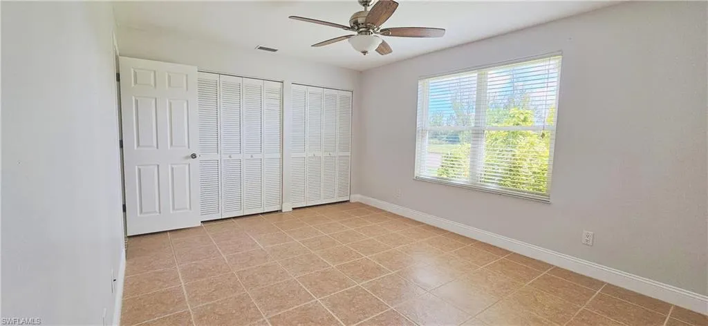 Unfurnished bedroom with ceiling fan, multiple closets, and  tile flooring