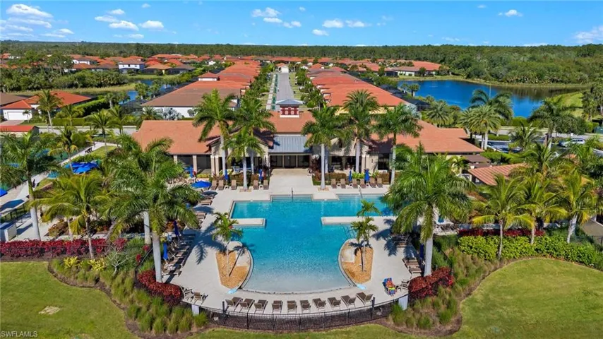 Resort-style pool area featuring multiple swimming pools, extensive lounge seating, and lush tropical landscaping