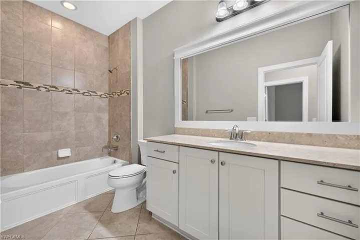 Bathroom featuring a white vanity with slab countertop, undermount sink, and brushed nickel fixtures