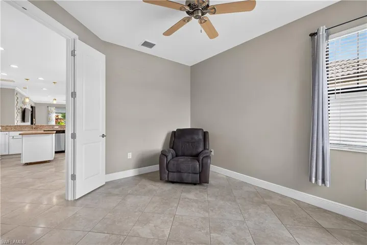 Neutral-toned room with tile flooring, a window featuring blinds and a curtain rod, and a ceiling fan