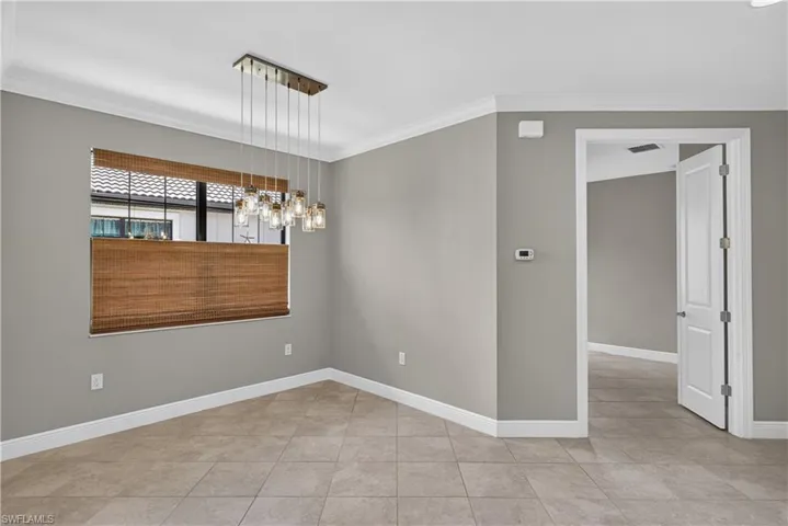 Dining area featuring tile flooring, a window with wood-finish blinds, and a multi-light pendant fixture