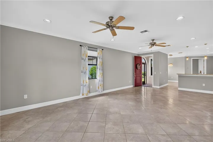 Living room with impact resistant front door leading to the screened entrance, upgraded tile floors, crown molding and 5 1/4" baseboards.