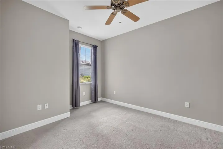 Carpeted bedroom featuring a window with blinds, ceiling fan, and light gray wall paint