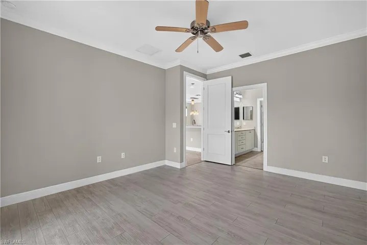 Spacious room featuring wood-finish flooring, neutral wall tones, and crown molding