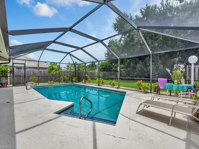 View of pool featuring glass enclosure and a patio area
