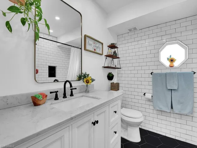 Bathroom with vanity, tile patterned floors, tile walls, toilet, and walk in shower