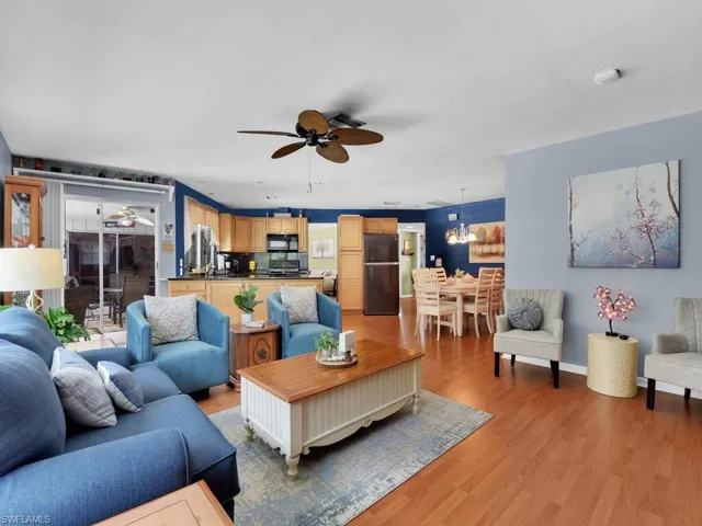 Living room featuring ceiling fan with notable chandelier and hardwood / wood-style flooring