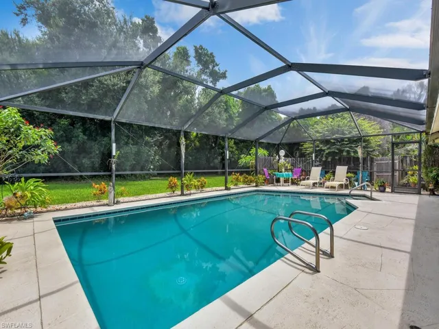View of pool with glass enclosure and a patio