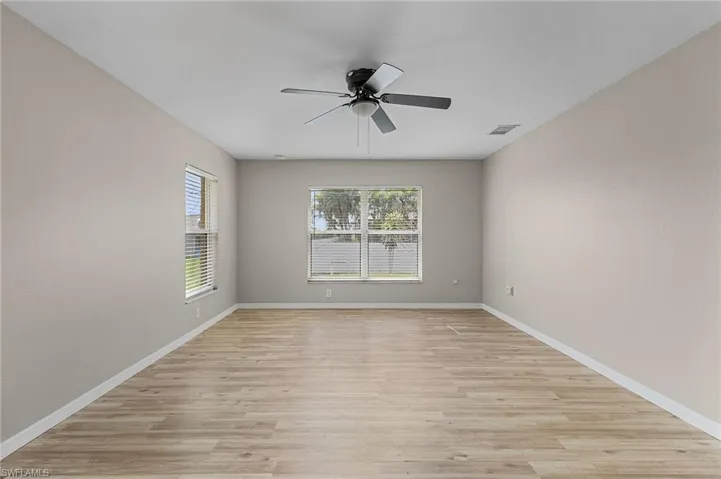 Large empty room with vinyl wood-type flooring and ceiling fan