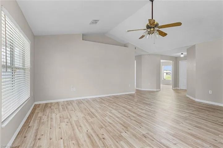 Unfurnished living room featuring ceiling fan, vaulted ceiling, and light wood-type flooring