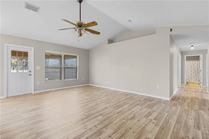 Unfurnished living room with ceiling fan, light wood-type flooring, and lofted ceiling