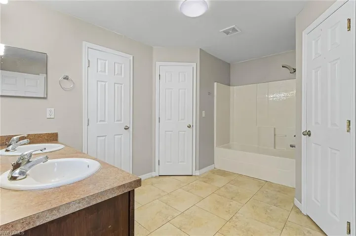 Bathroom with tile floors, shower / bath combination, water closet, linen closet, and dual bowl vanity