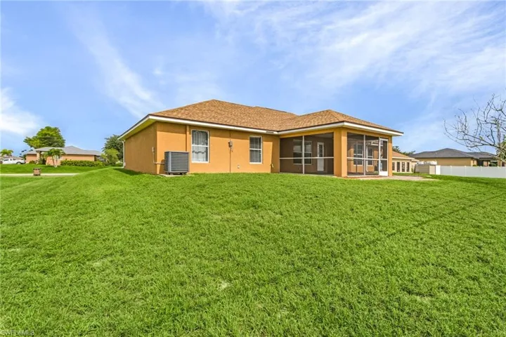Rear view of house with a yard, a screened lanai/porch, and central air condition unit