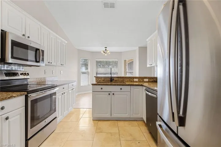 Kitchen featuring granite countertops, sink, white cabinetry, and stainless steel appliances