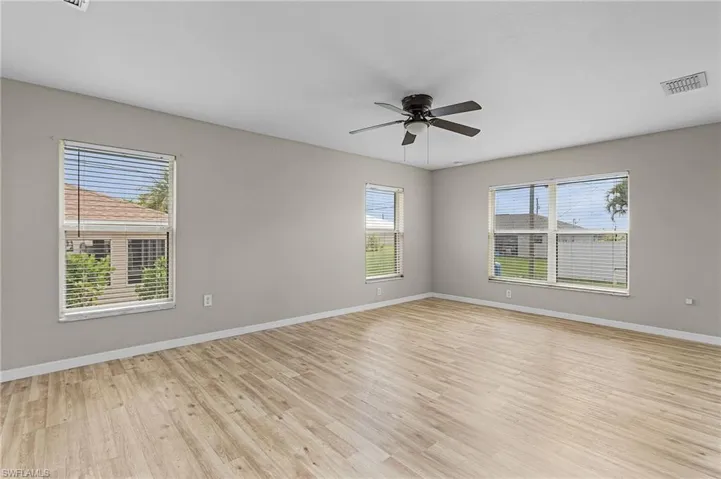 Large unfurnished room featuring ceiling fan and vinyl wood-style floors