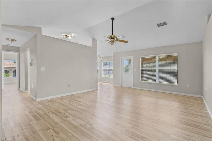 Unfurnished living room with a wealth of natural light, lofted ceiling, light wood-type flooring, and ceiling fan
