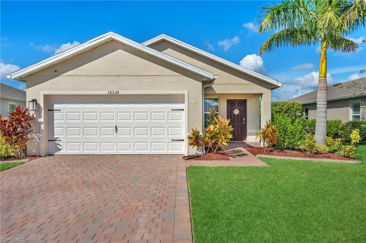 Single story home with decorative driveway, stucco siding, a front yard, and a garage