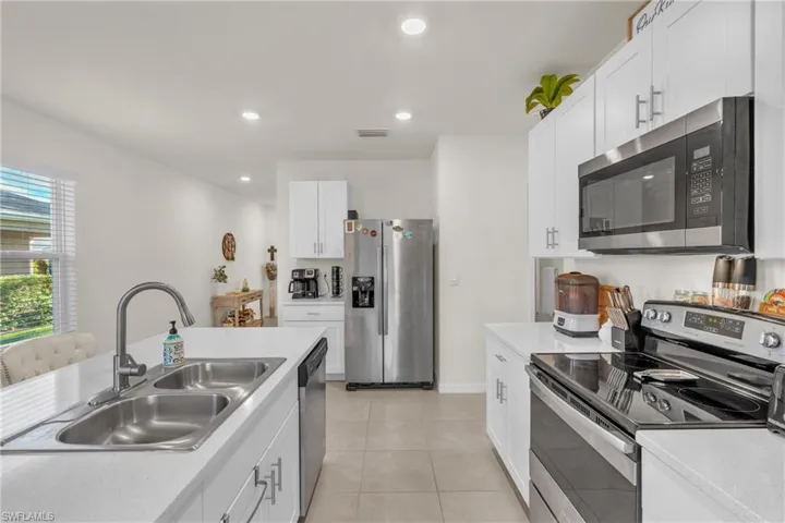 Kitchen featuring stainless steel appliances, white cabinets, light countertops, recessed lighting, and light tile patterned flooring