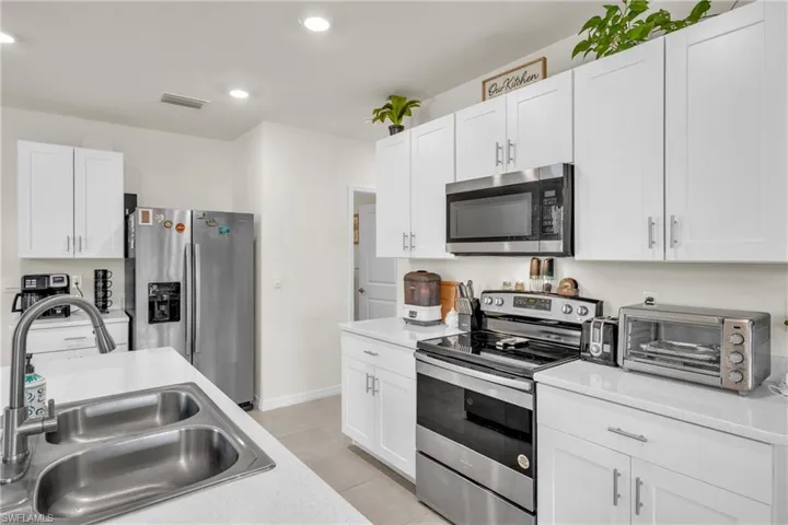 Kitchen with stainless steel appliances, white cabinetry, light tile patterned floors, and recessed lighting