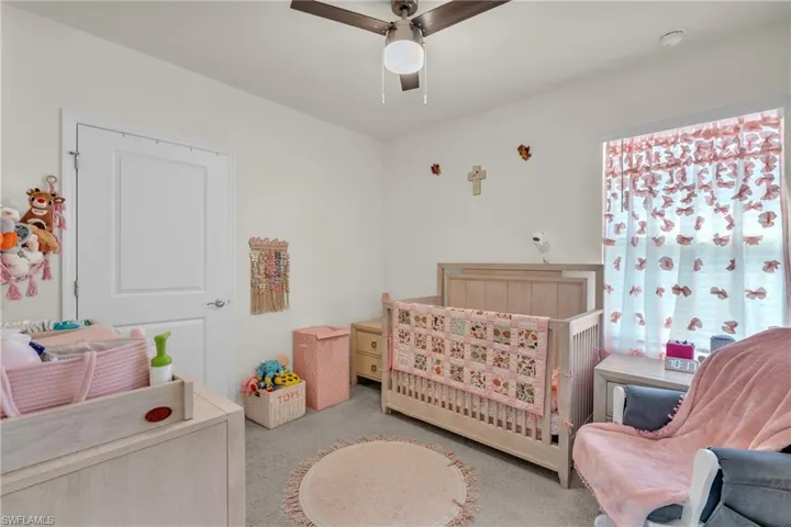 Bedroom with carpet floors, a nursery area, and ceiling fan