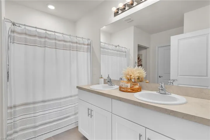 Bathroom featuring double vanity, curtained shower, and light tile patterned floors