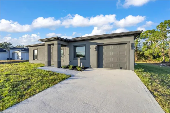 View of front facade featuring stucco siding, a front yard, and concrete driveway