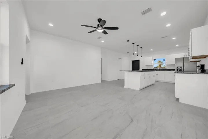 Kitchen with white cabinets, open floor plan, decorative light fixtures, recessed lighting, and stainless steel fridge with ice dispenser