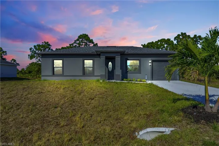 Prairie-style house featuring stucco siding, an attached garage, a lawn, and concrete driveway