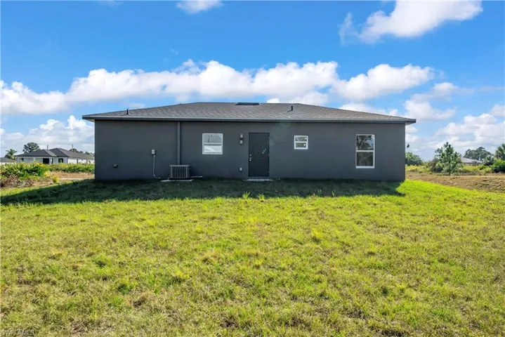 Rear view of property featuring a lawn and stucco siding