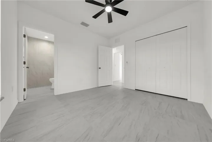 Unfurnished bedroom featuring ceiling fan, a closet, and ensuite bath