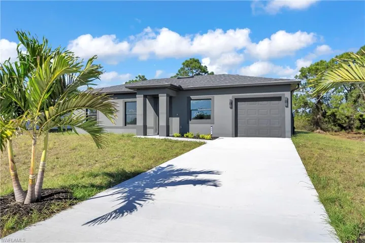 View of front facade with stucco siding, a garage, concrete driveway, a front lawn, and a shingled roof