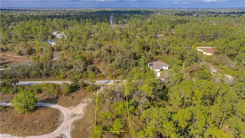Aerial view of property and surrounding area with a heavily wooded area and property parcel outlined