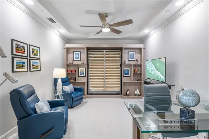Home office with tile floors, ceiling fan, a raised ceiling, and ornamental molding