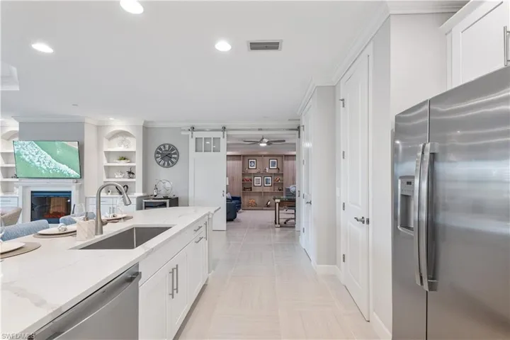 Kitchen with ceiling fan, white cabinetry, light stone countertops, appliances with stainless steel finishes, and sink