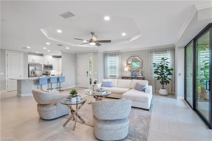 Living room with a tray ceiling, plenty of natural light, ceiling fan, and light tile floors