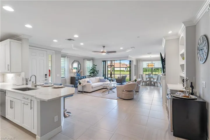 Kitchen featuring white cabinets, sink, ceiling fan, and light tile flooring